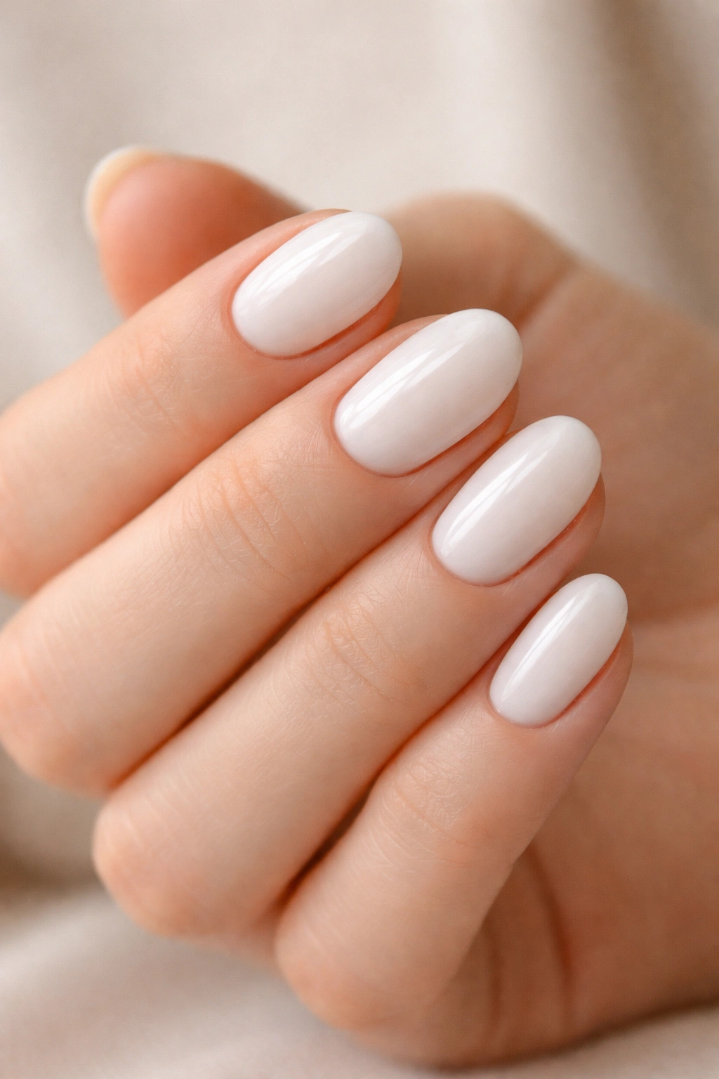 Close-up of short oval nails painted milky white with a soft creamy finish and smooth surface