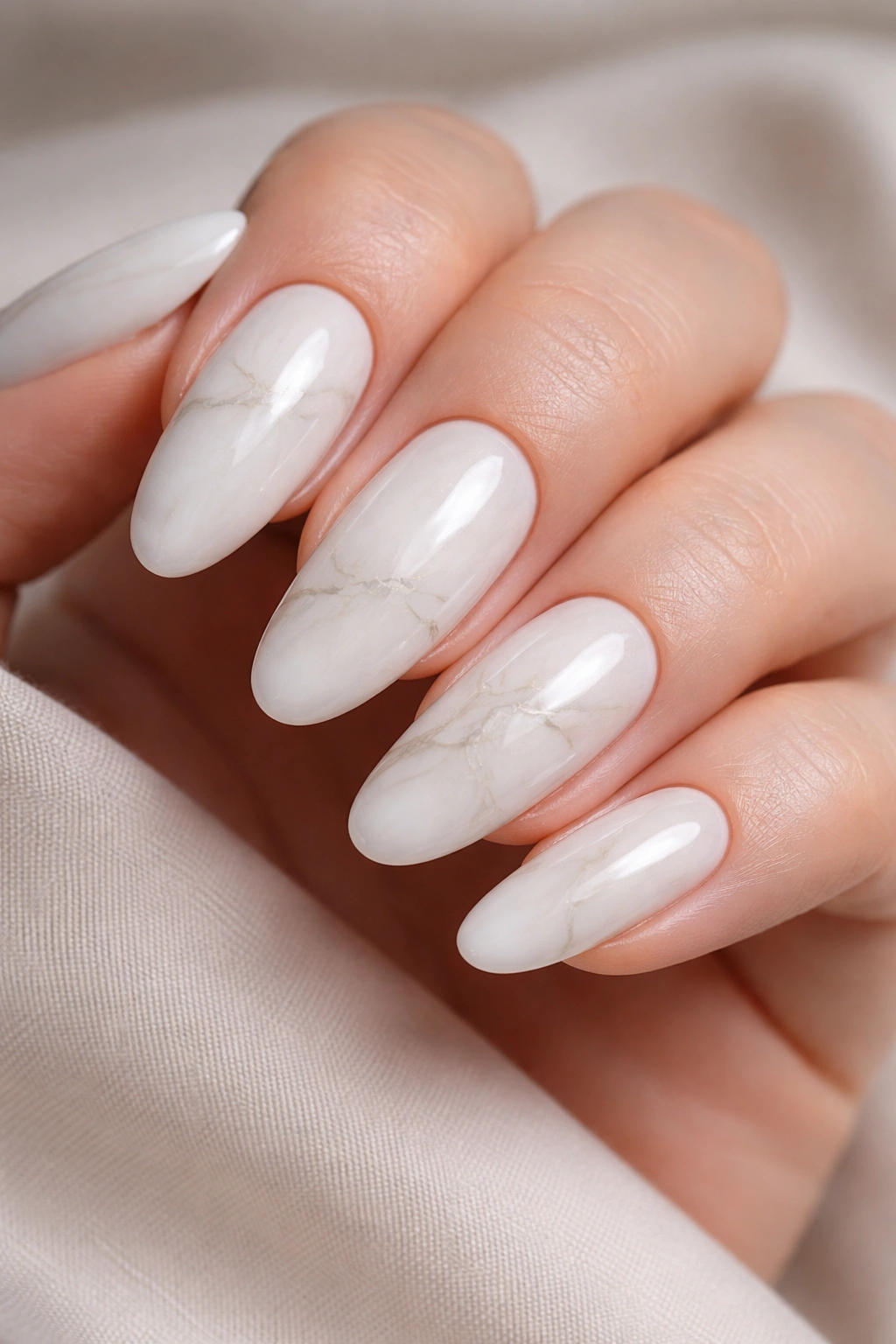 Close-up of milky white long oval nails with subtle marble veining