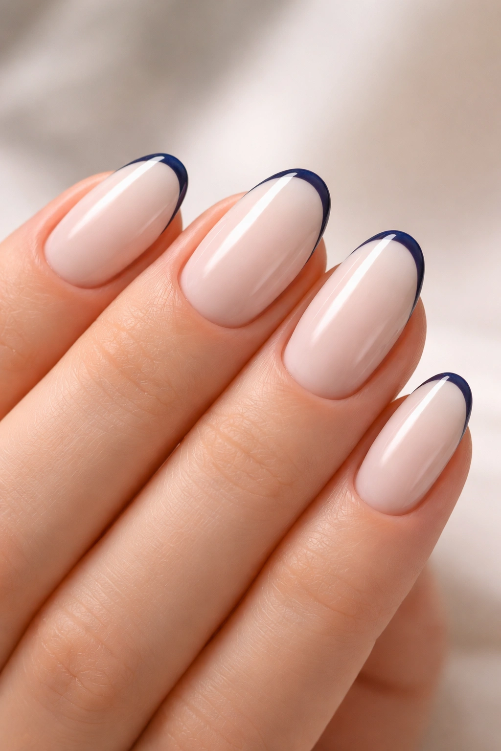 Close-up of short almond nail with milky white base and razor-thin navy edge line