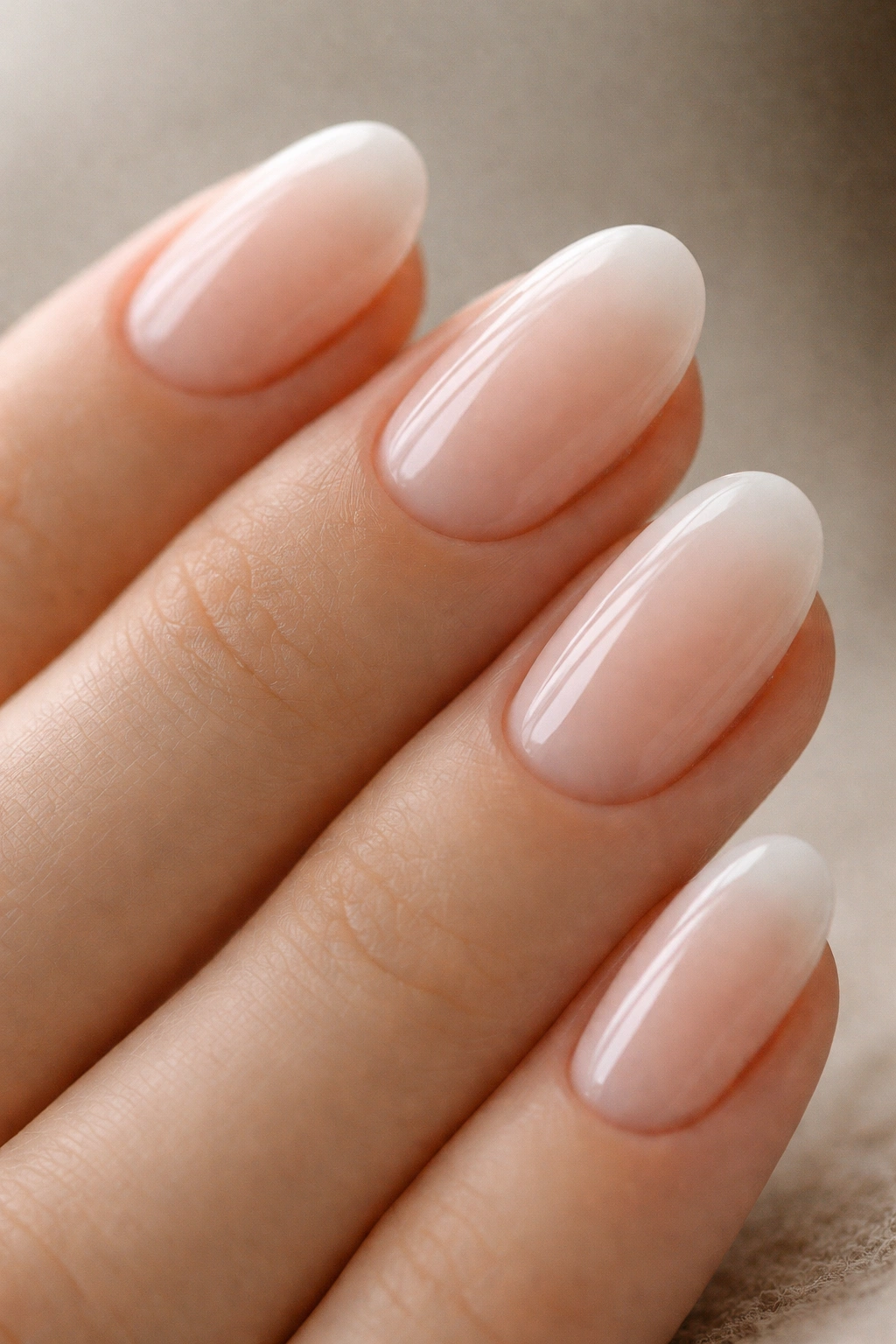 Short oval nails with milky white tips and a soft blur on a blush base