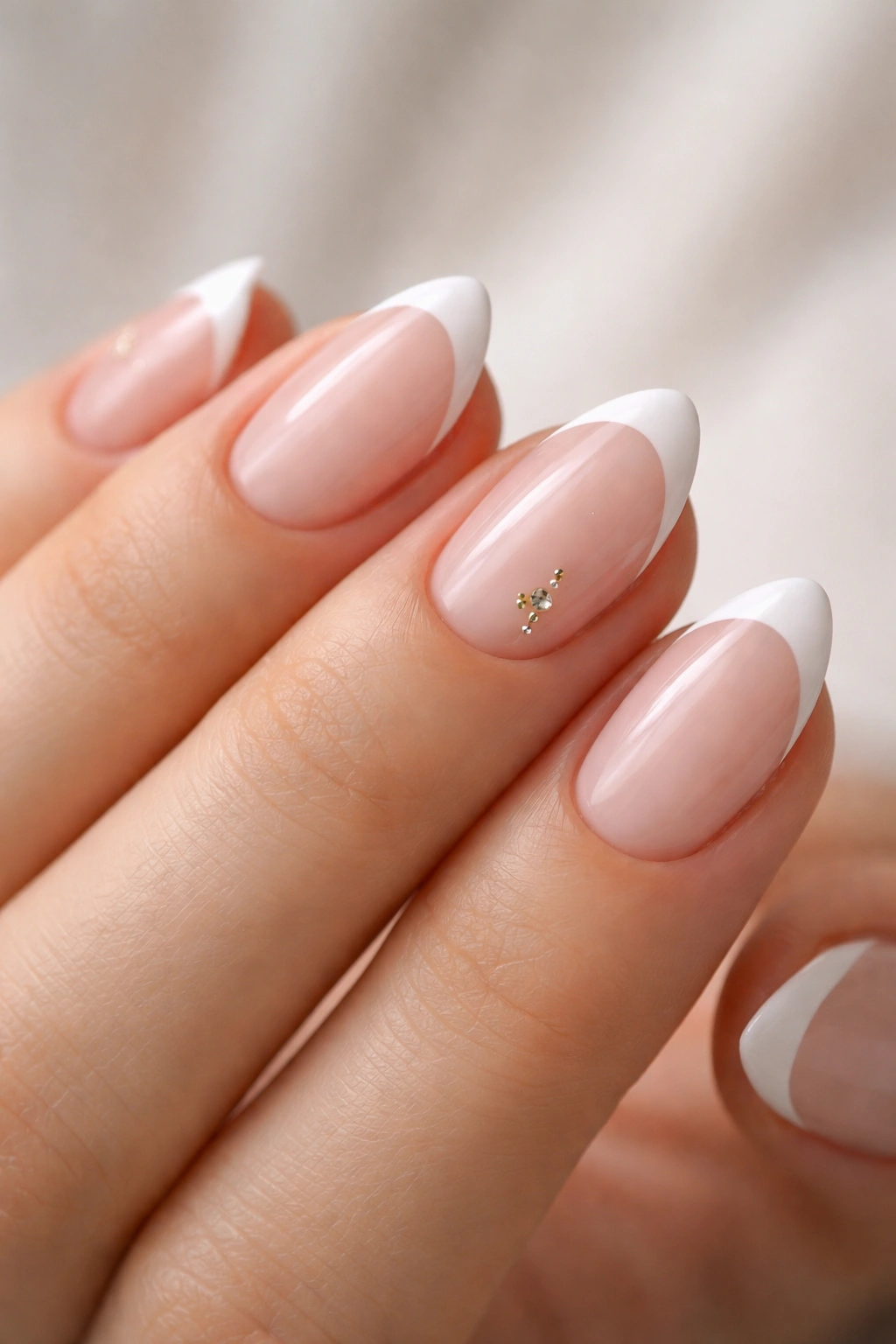 Close-up of minimal French tips with tiny accent on short almond nails