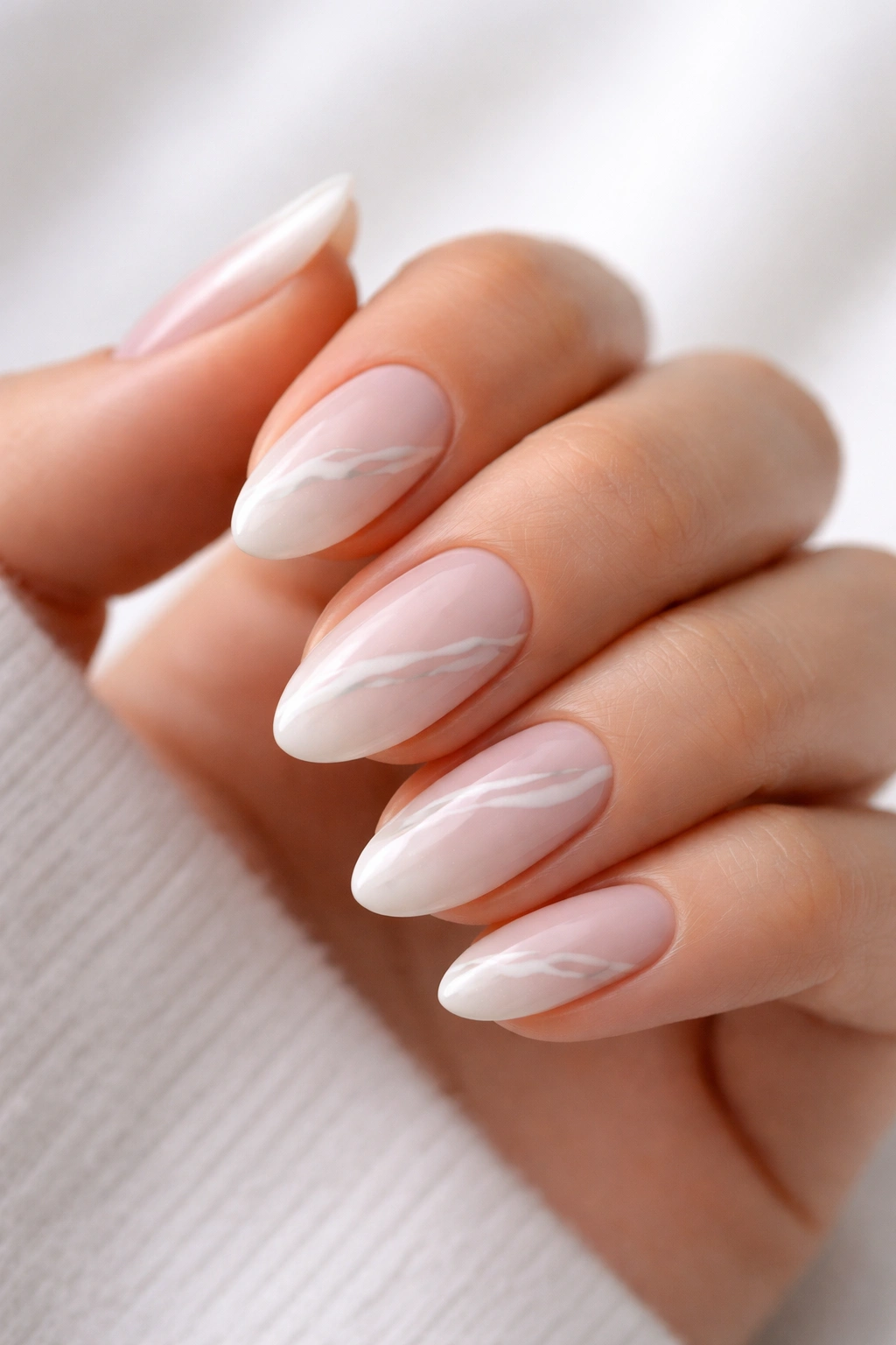 Close-up of short almond nails with minimal marble lines and negative space