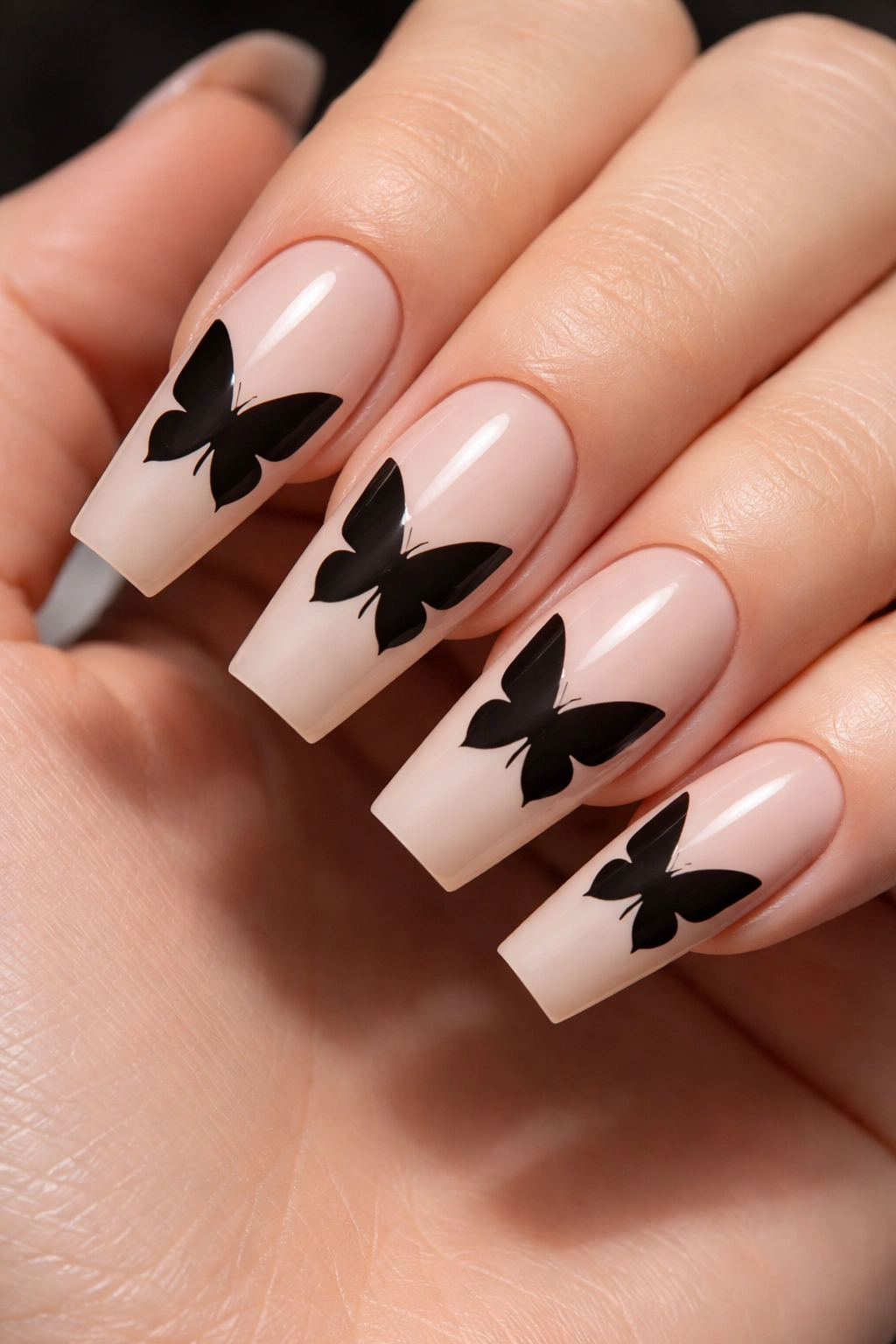 Nude coffin nails with a single solid black butterfly silhouette.