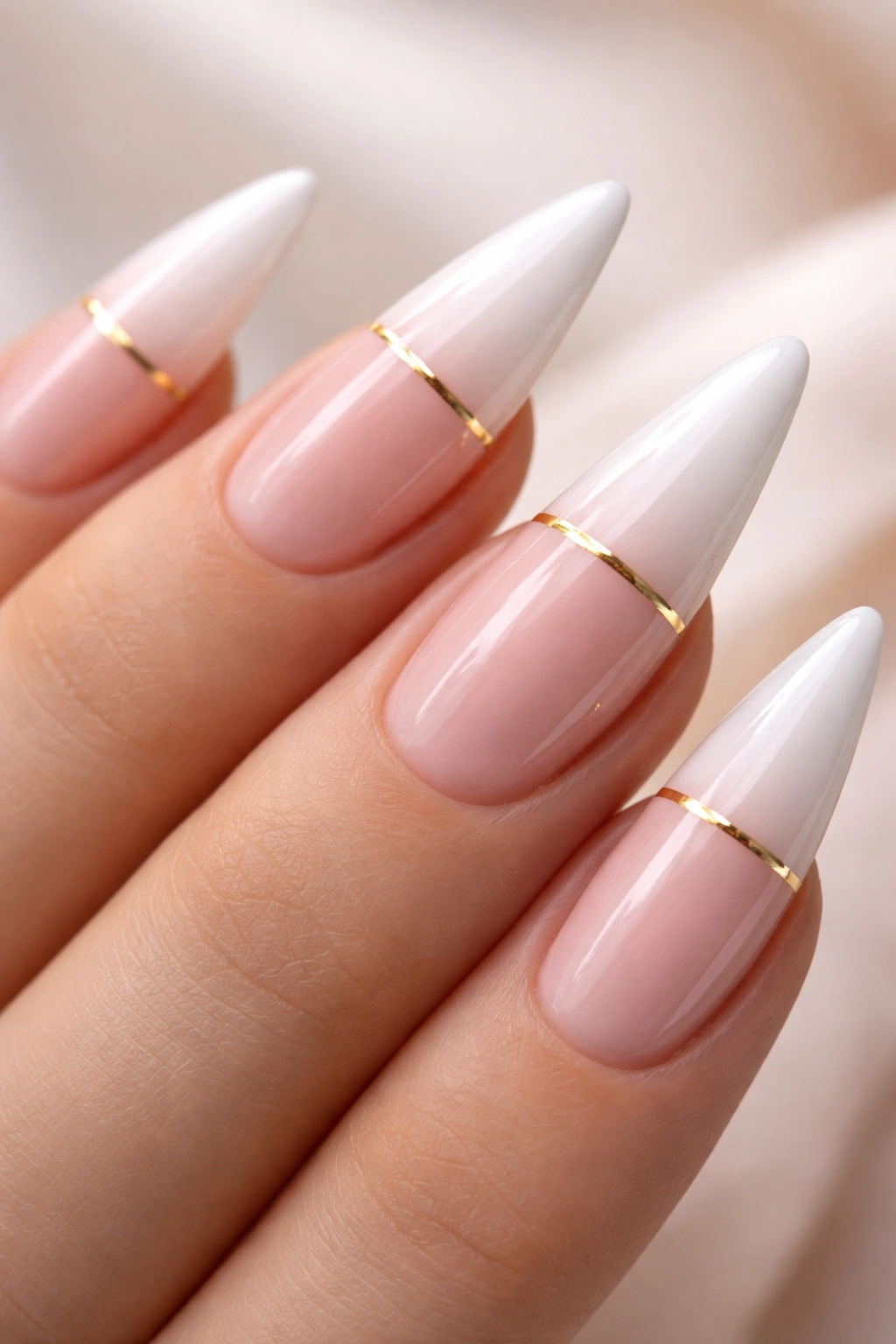 Close-up of white stiletto nails with a thin gold line on the French tip