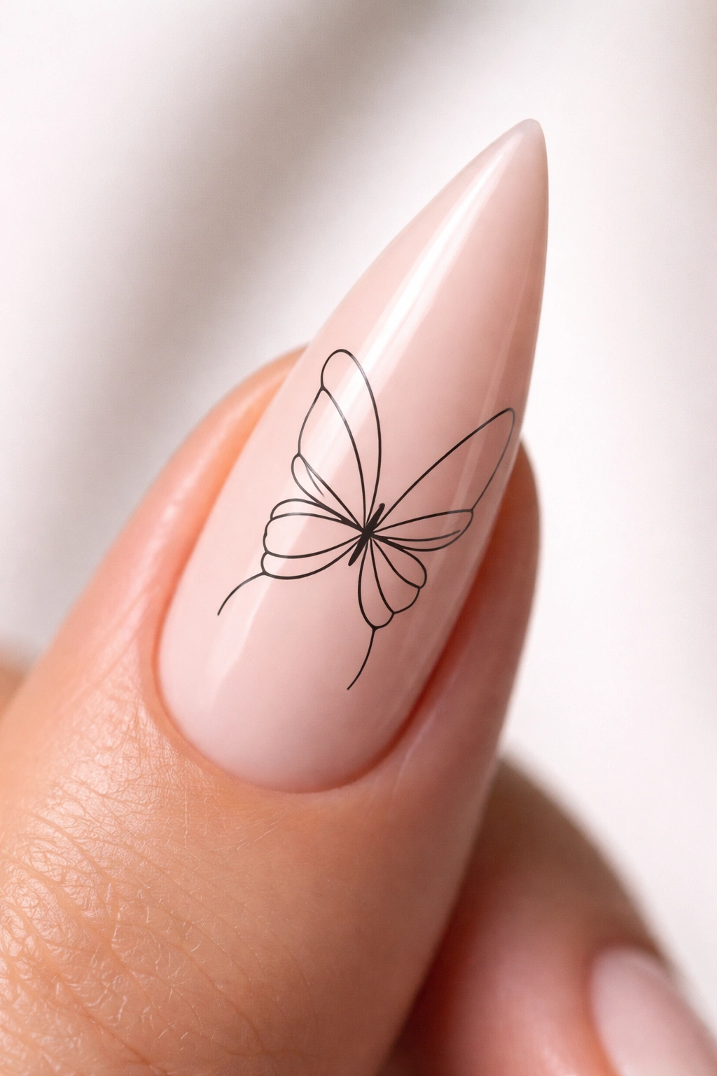 Close-up of minimalist line-art butterfly on a nude stiletto nail