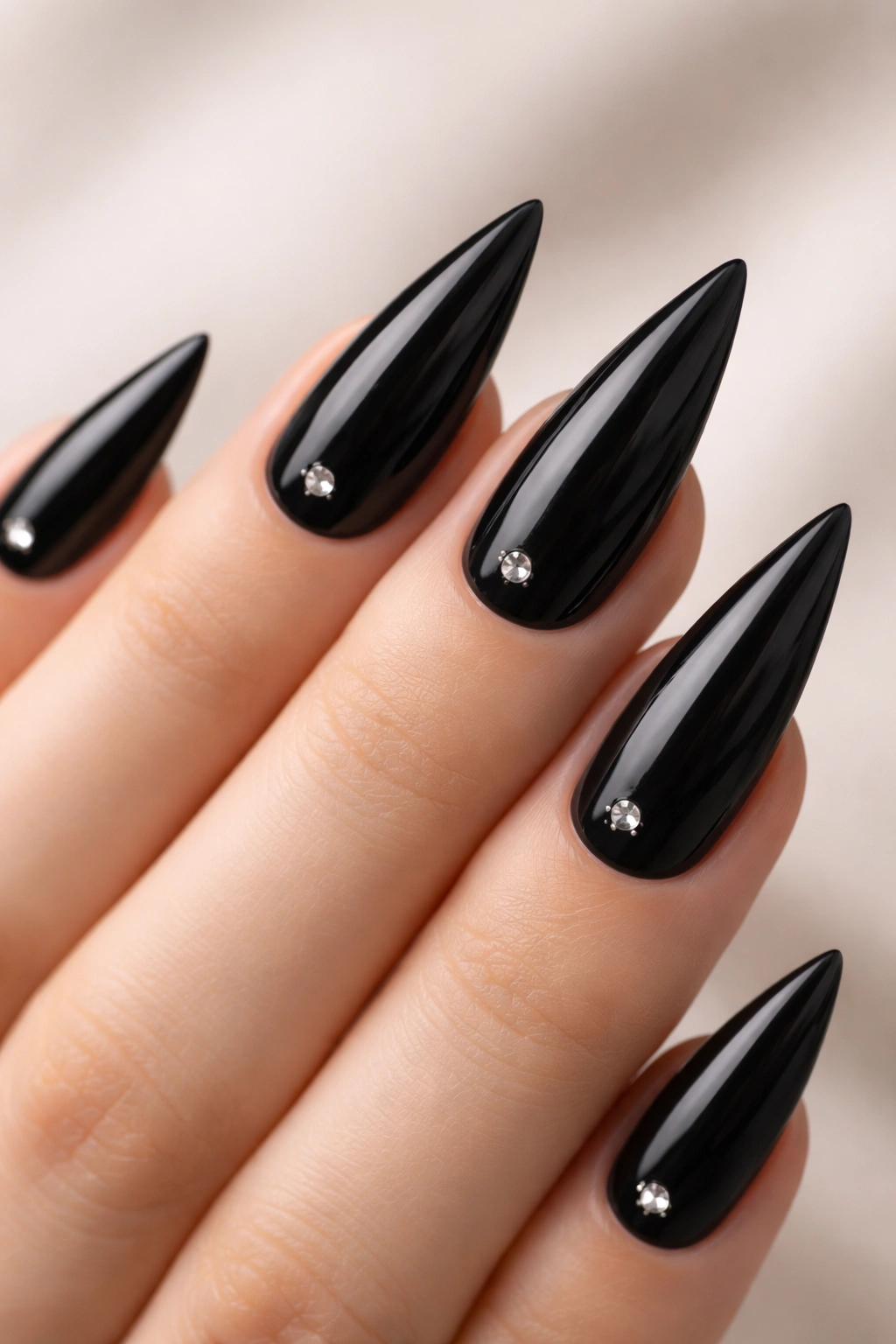 Black stiletto nails each with a single small centered rhinestone