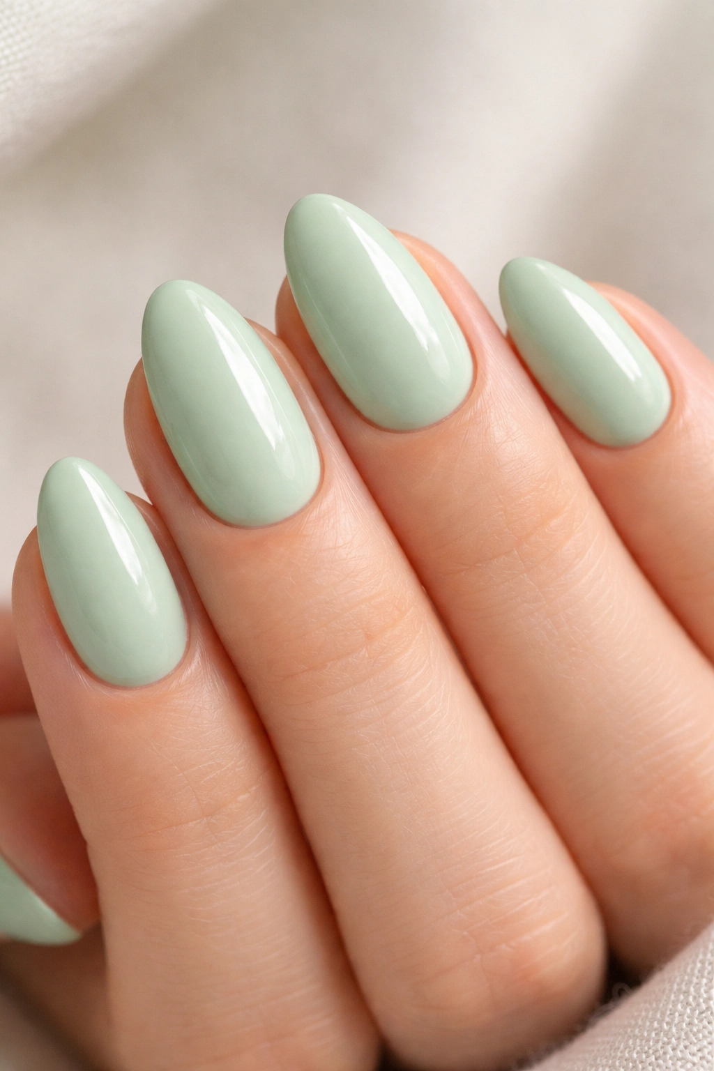 Close-up of short almond nails mint green glossy finish
