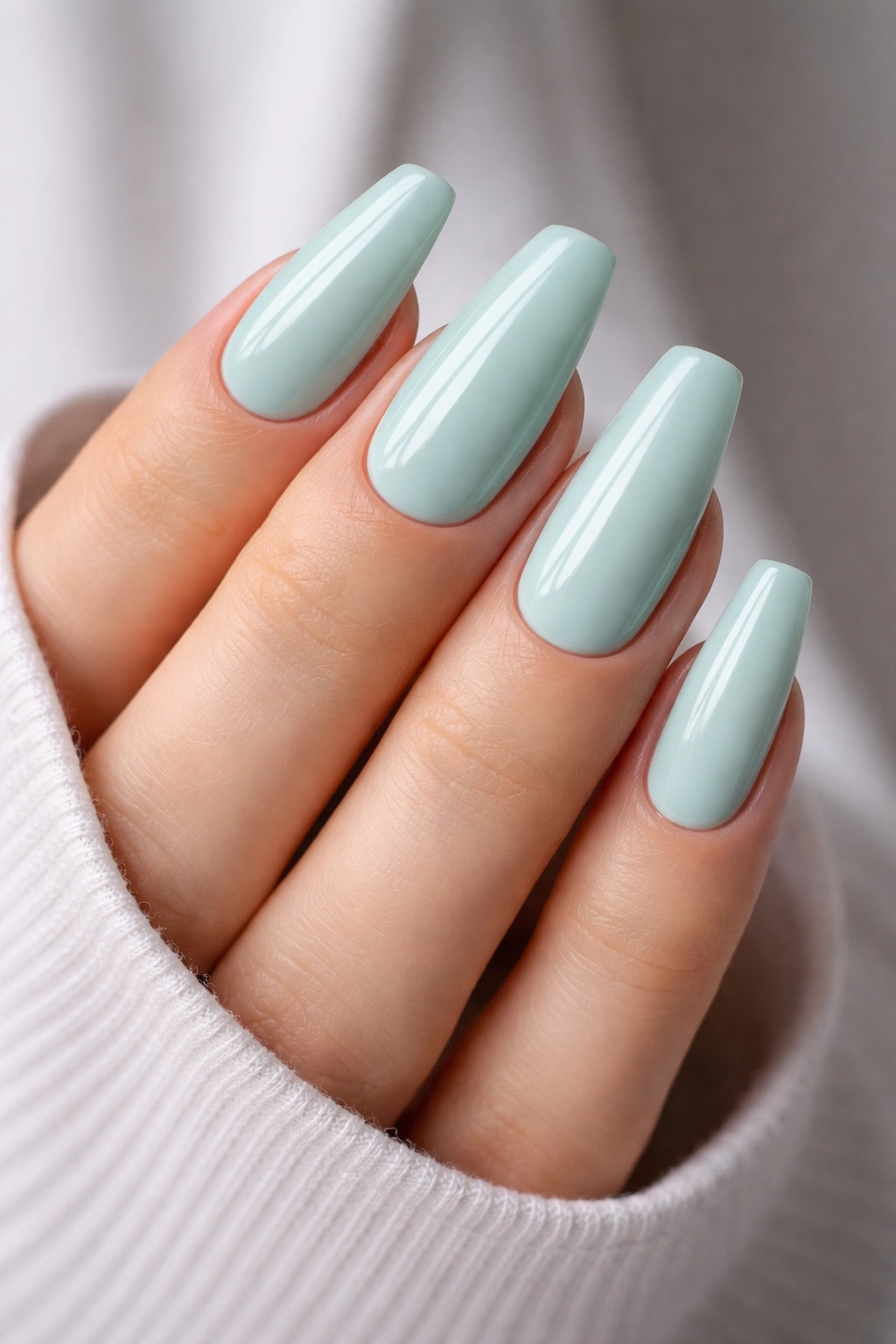 Close-up of medium coffin nails painted cool mint green with a glossy finish