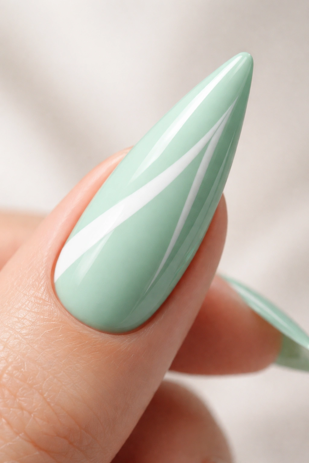 Mint green stiletto nail with white geometric accent.