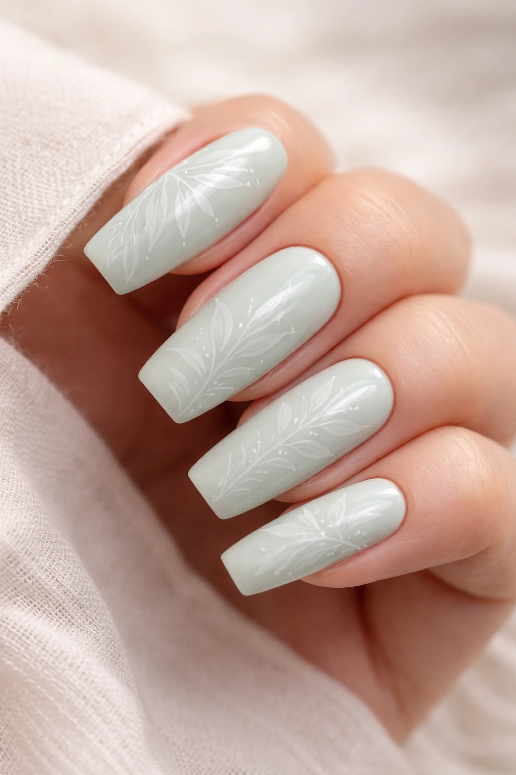 Close-up of pale mint green coffin nails with delicate line art