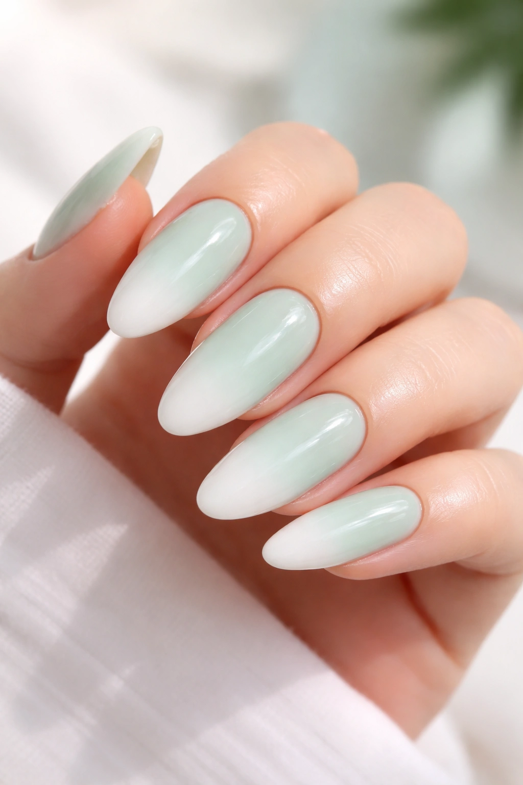 Close-up of long oval nails in mint to white ombre with glossy finish