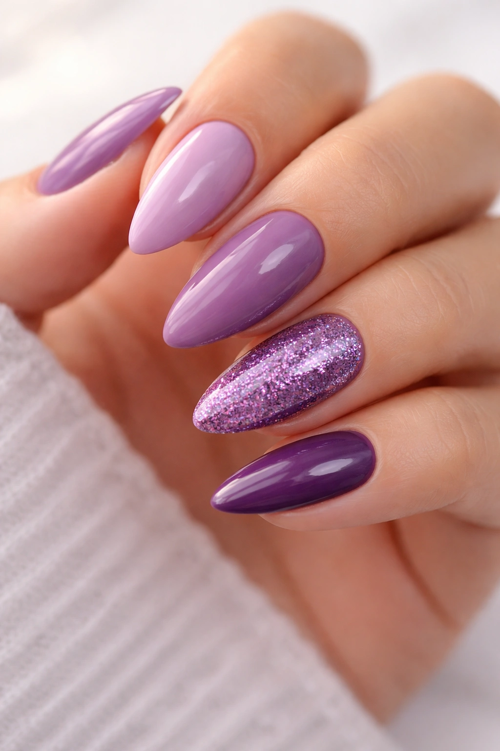 Almond nails arranged in a cohesive mix of purple shades with a glitter accent