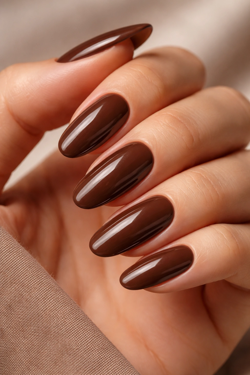 Close-up of long oval mocha brown nails with glossy finish