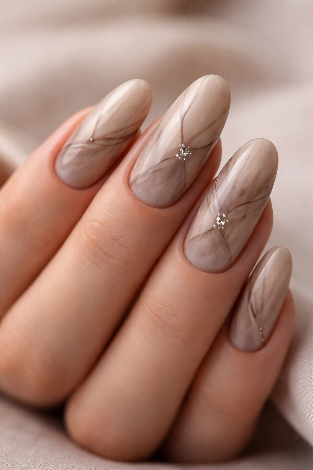 Close-up of mocha marble long oval nails with rhinestones tucked into the veins