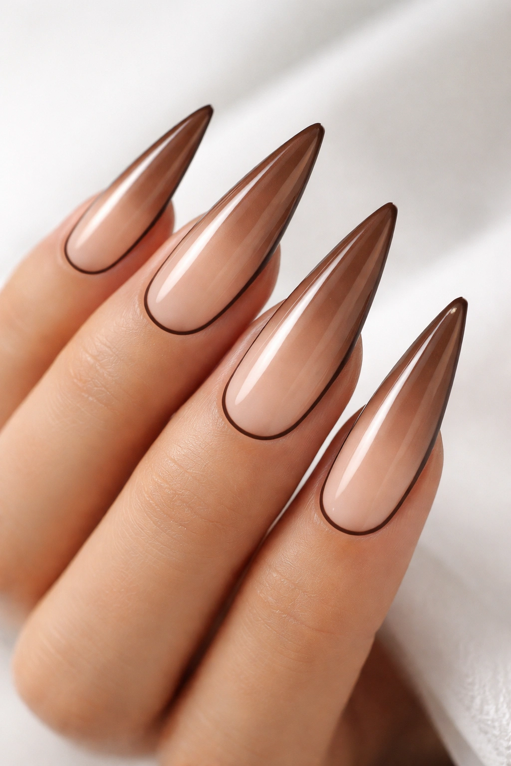 Mocha-to-nude ombre stiletto nails with negative space and outline.