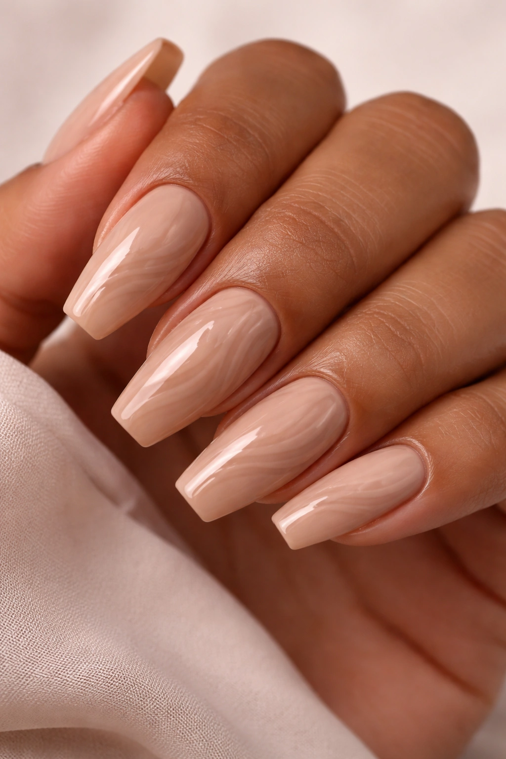 Mocha nude nails with tonal swirl lines on a ballerina shape under soft lighting