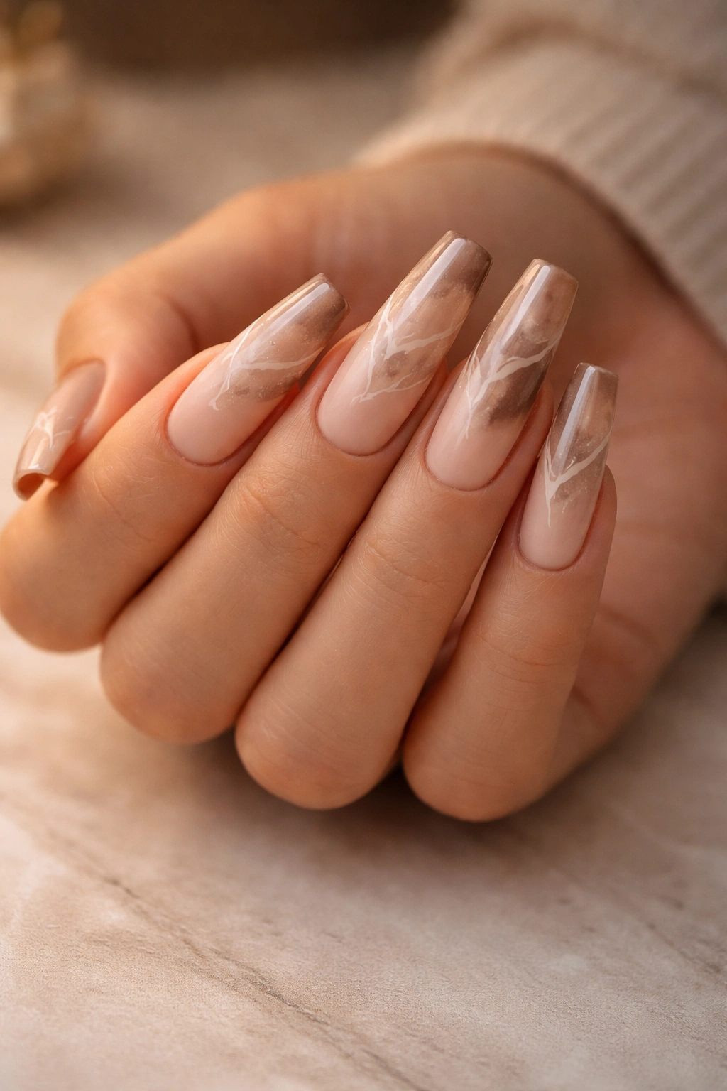 Close-up of mocha ombre marble nails with a gradient from light to dark and marble veining
