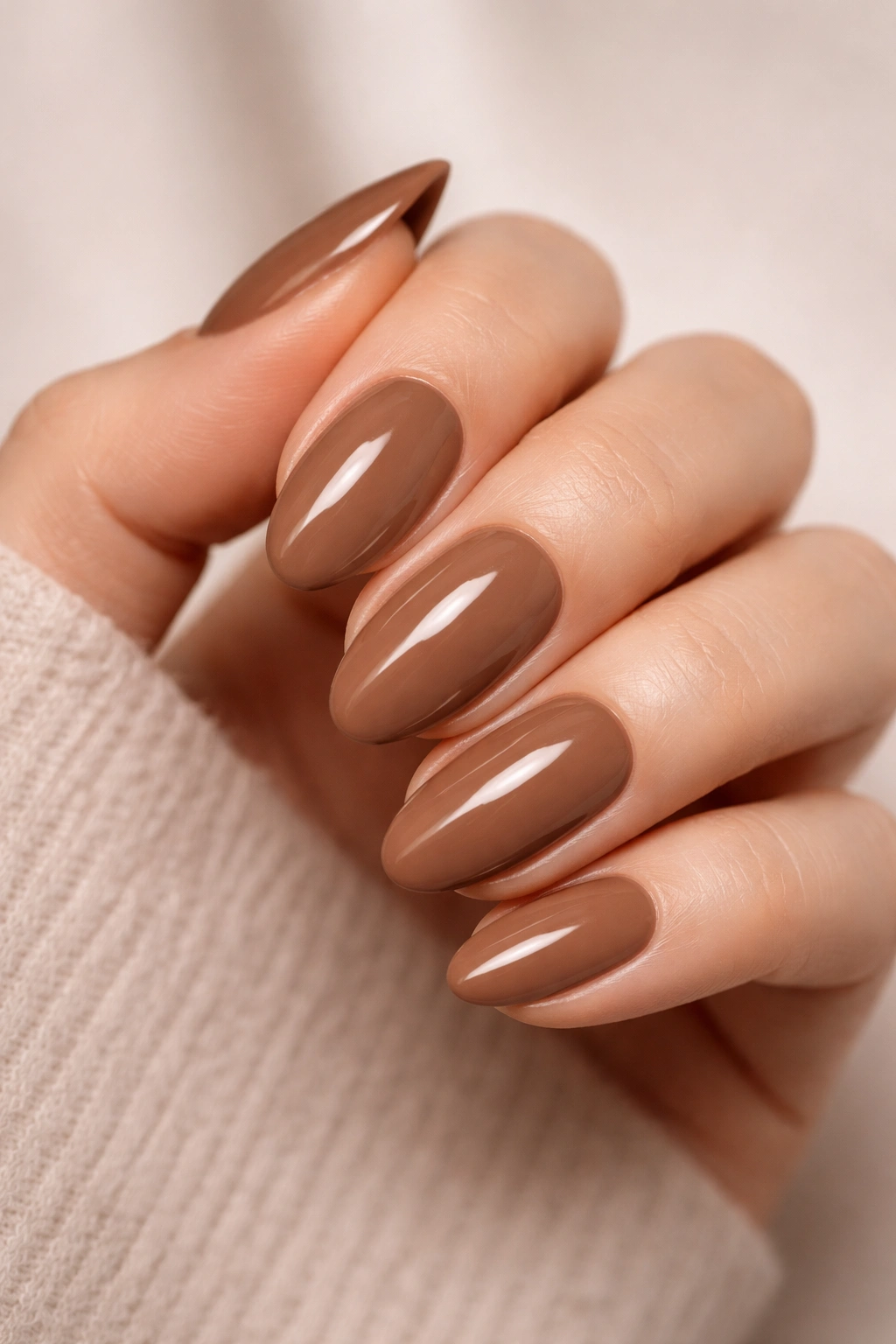 Close-up of solid mocha nails on a hand with glossy warm brown polish