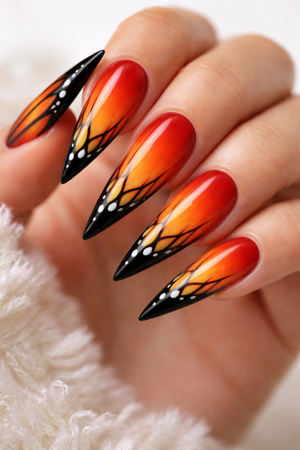 Close-up of monarch wing gradient on stiletto nails with orange tones