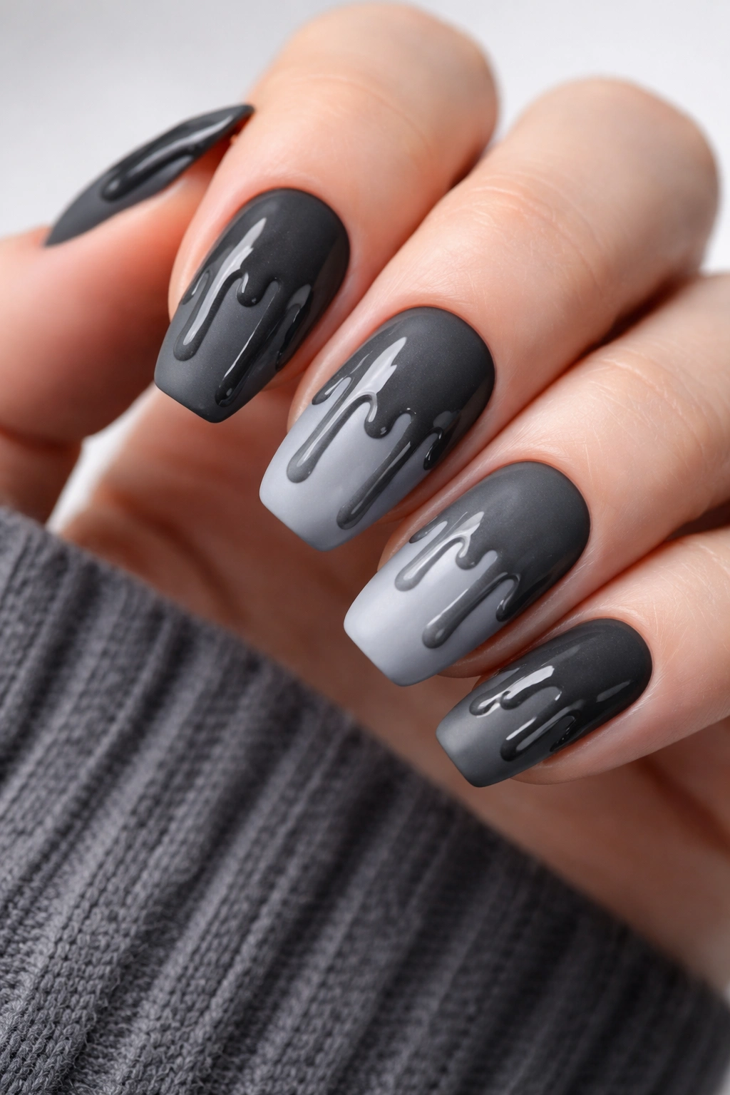 Close-up of charcoal to light gray nails with matte base and glossy gray drips