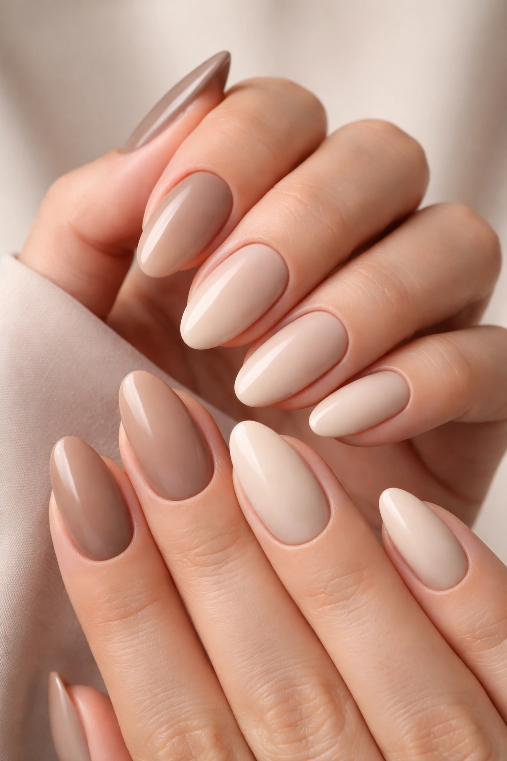 Close-up of nails with a monochrome ombré gradient from dark to light in beige to cream tones.