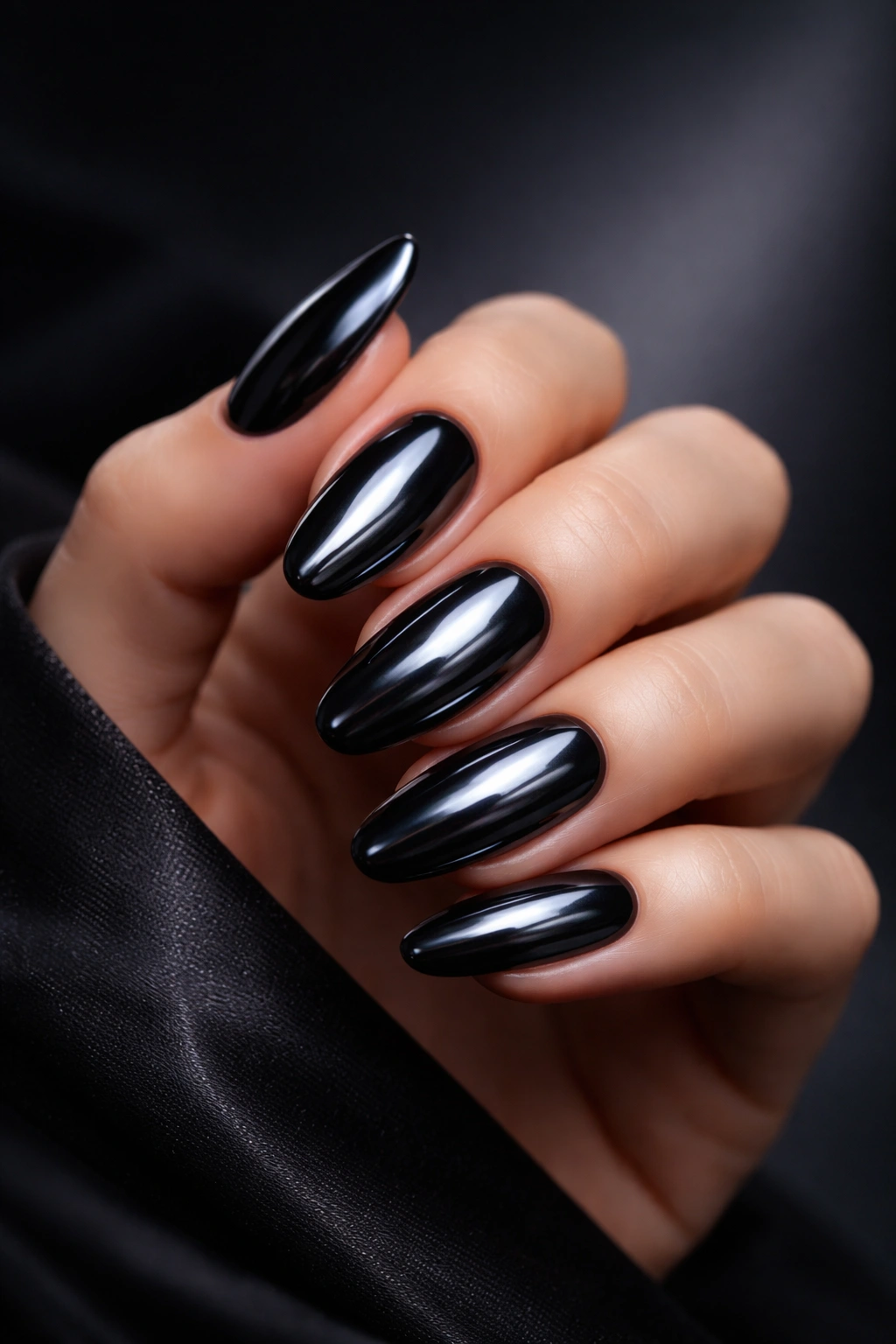 Close-up of hand with dark chrome nails in moody studio setting.