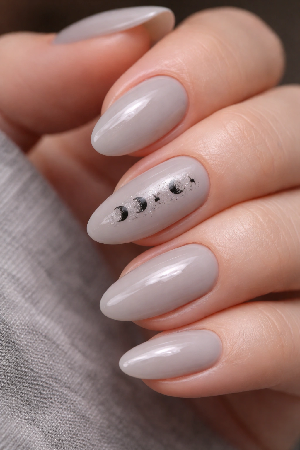 Short almond nails with moon phase designs on milky gray base
