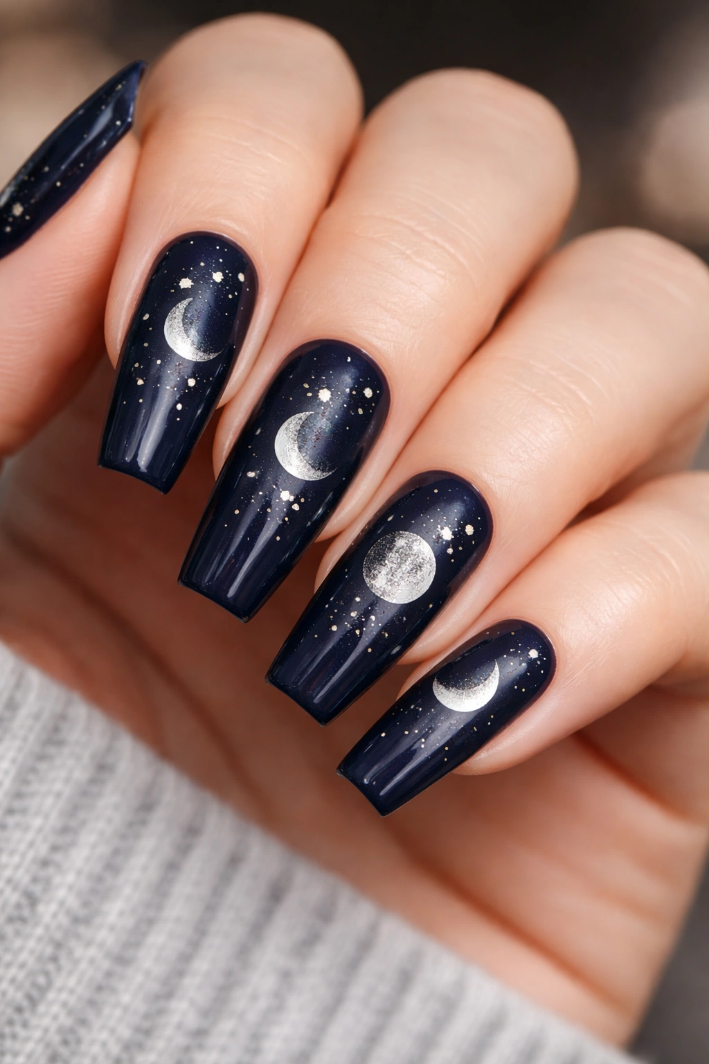 Close-up of moon phase nails on deep navy coffin nails