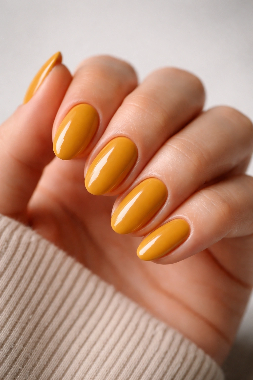 Close-up of short almond nails in mustard yellow polish