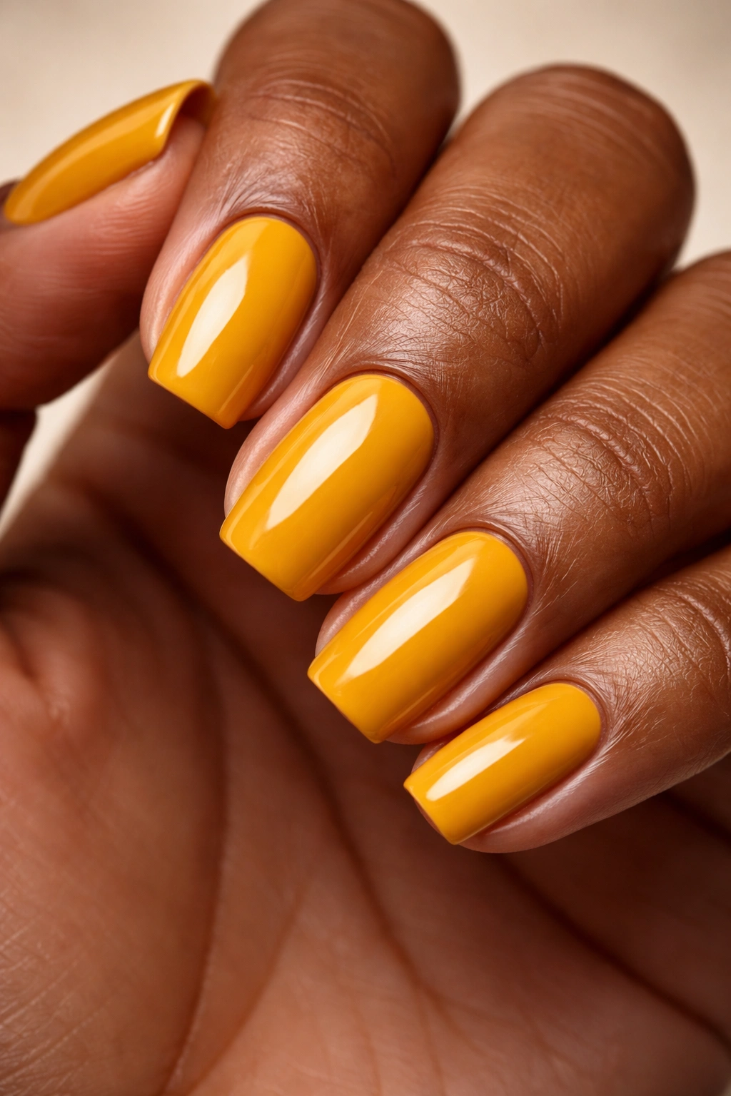 Close-up nails painted mustard yellow with warm undertones