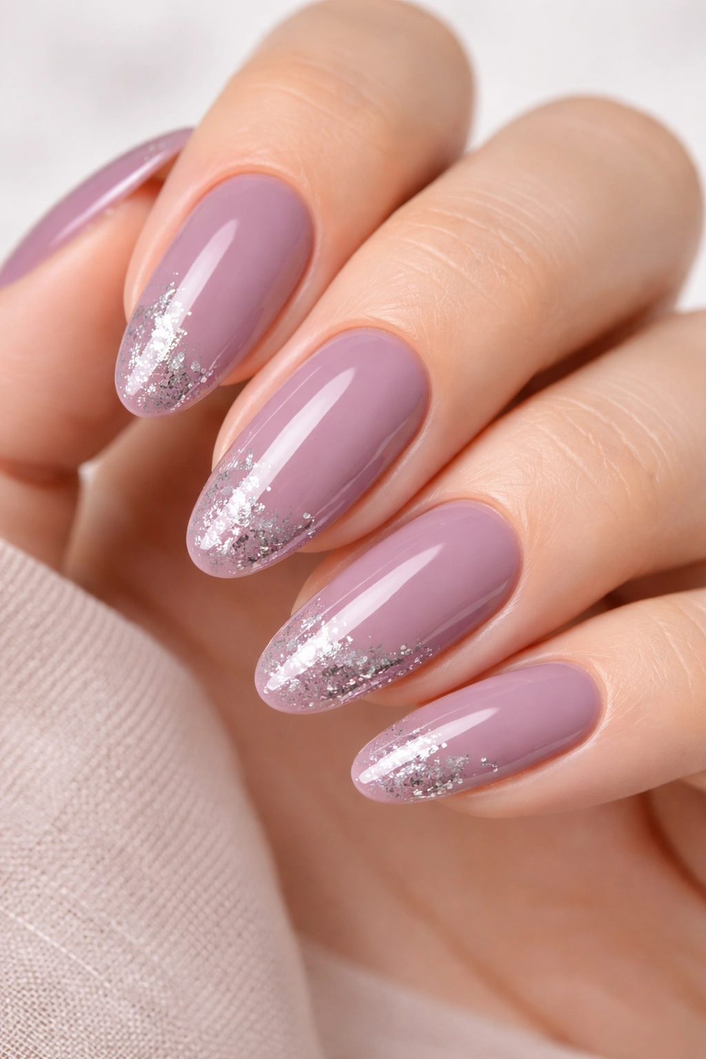 Close-up of muted mauve nails with silver foil details on long round nails