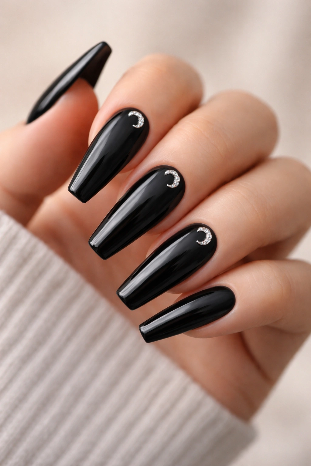 Jet black nails with a single crescent crystal near the cuticle