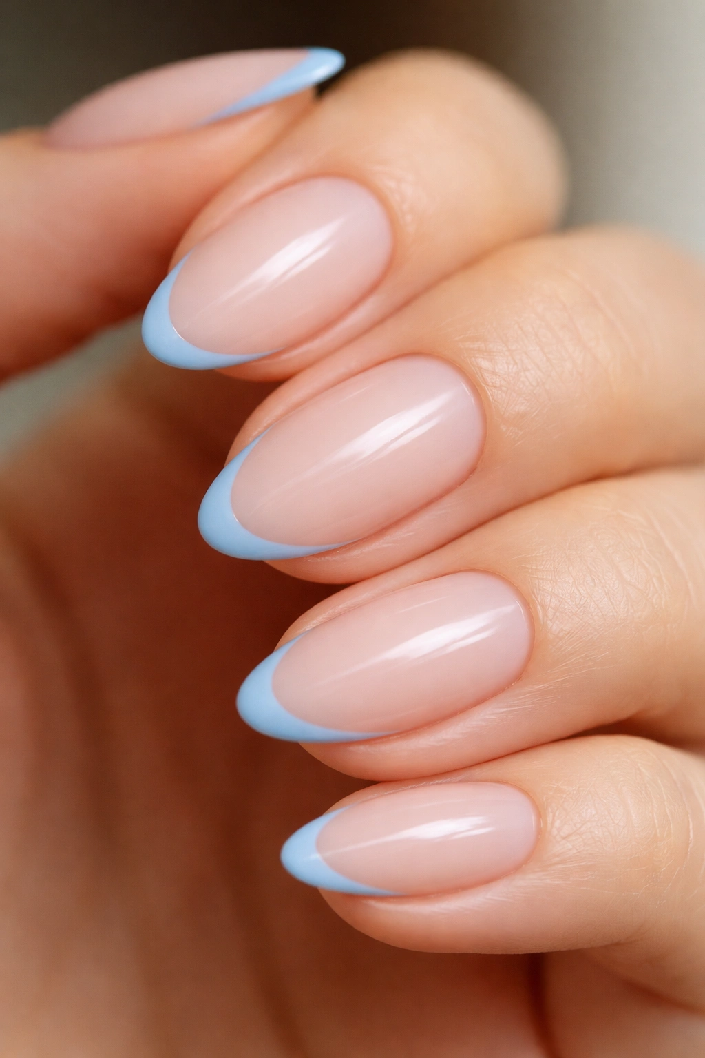 Extreme close-up of nude almond nail with a micro sky blue hairline French tip.