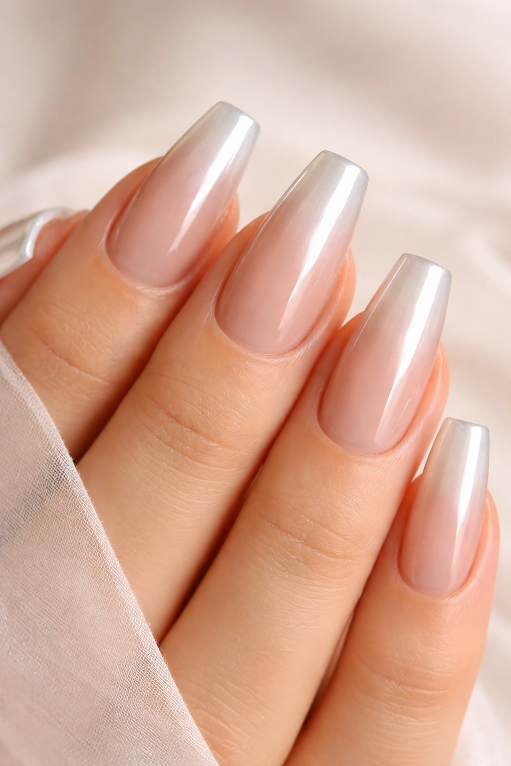 Close-up of sheer nude nails with pearly white chrome tips on ballerina nails