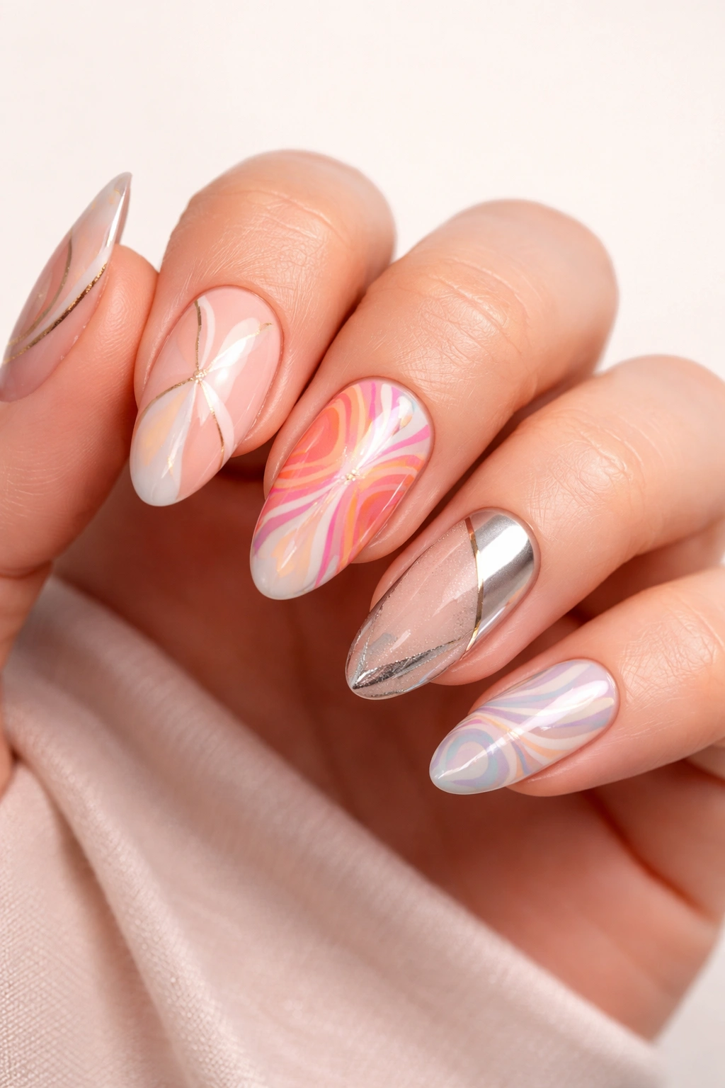 Hand with varied nail art designs on different nails.