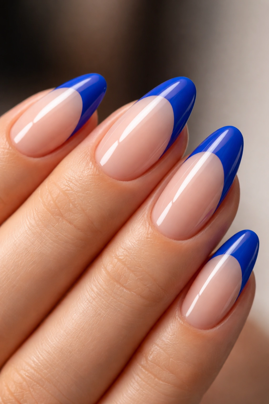 Close-up of almond nail with electric blue tip and negative space at the base.