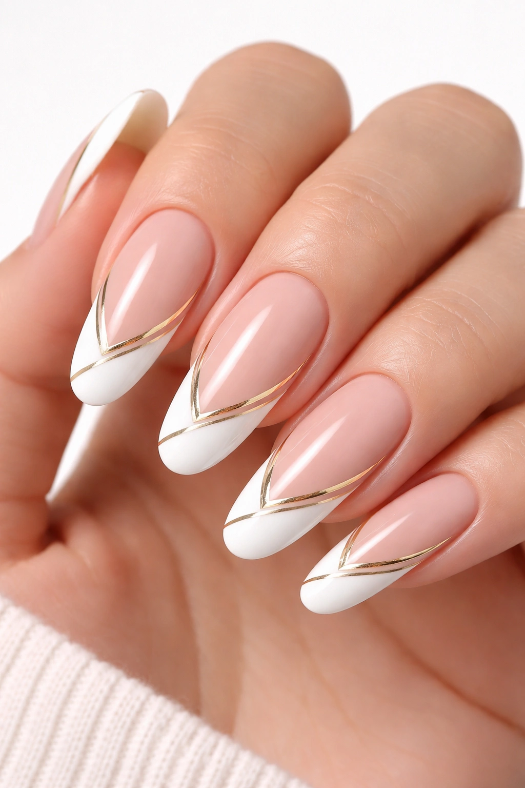 Geometric gold-lined tips on long round nails with crisp white edge in studio light.