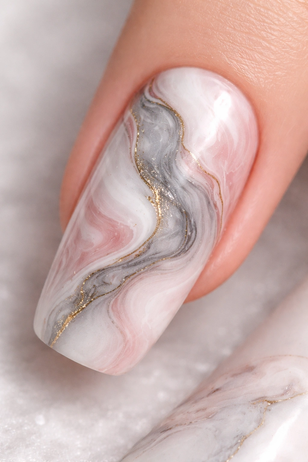 Close-up of a fingernail with blooming gel marble swirl in white gray pink and gold