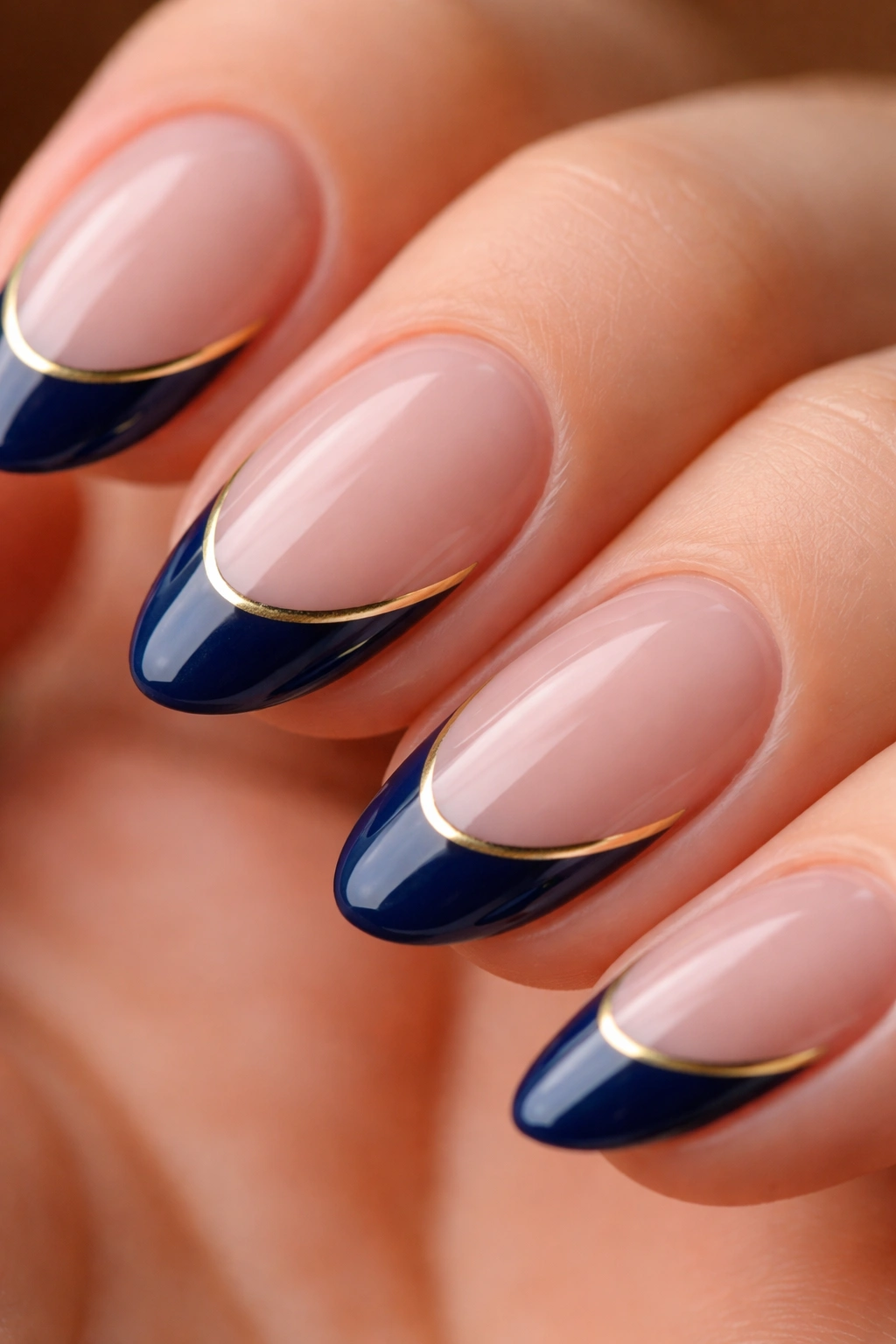 Close-up of short almond nail with midnight blue tip and gold chrome liner.