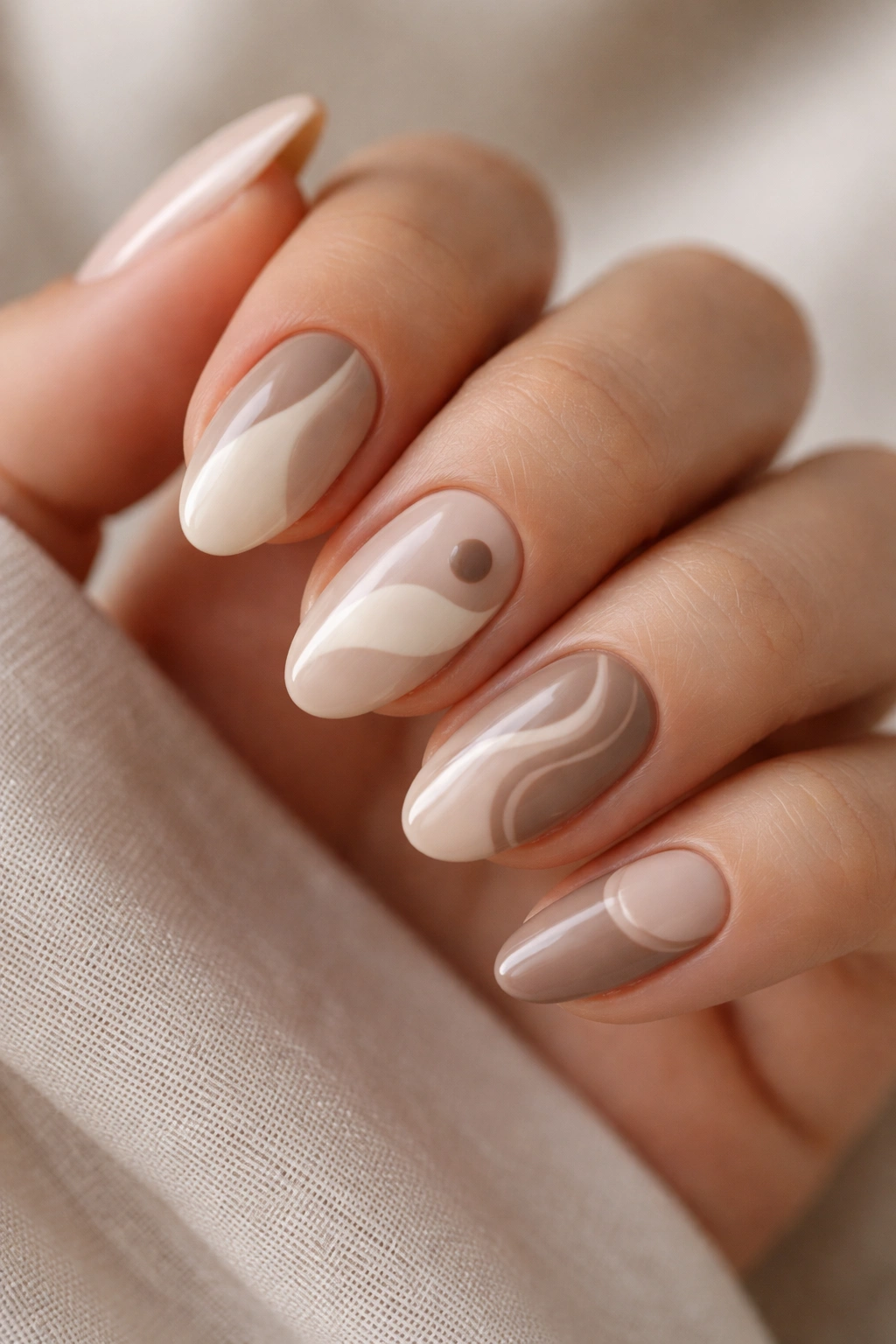 Close-up of short almond nails with varied neutral shapes in beige tones