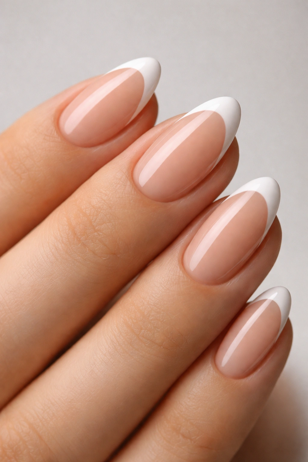 Close-up of an extra-short almond nail with nude base and curved white smile line.
