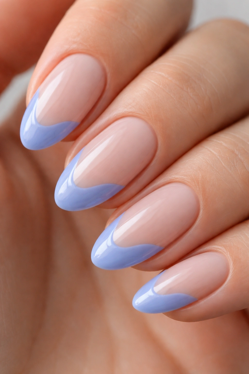 Close-up of almond nail with periwinkle blue wavy French tip.