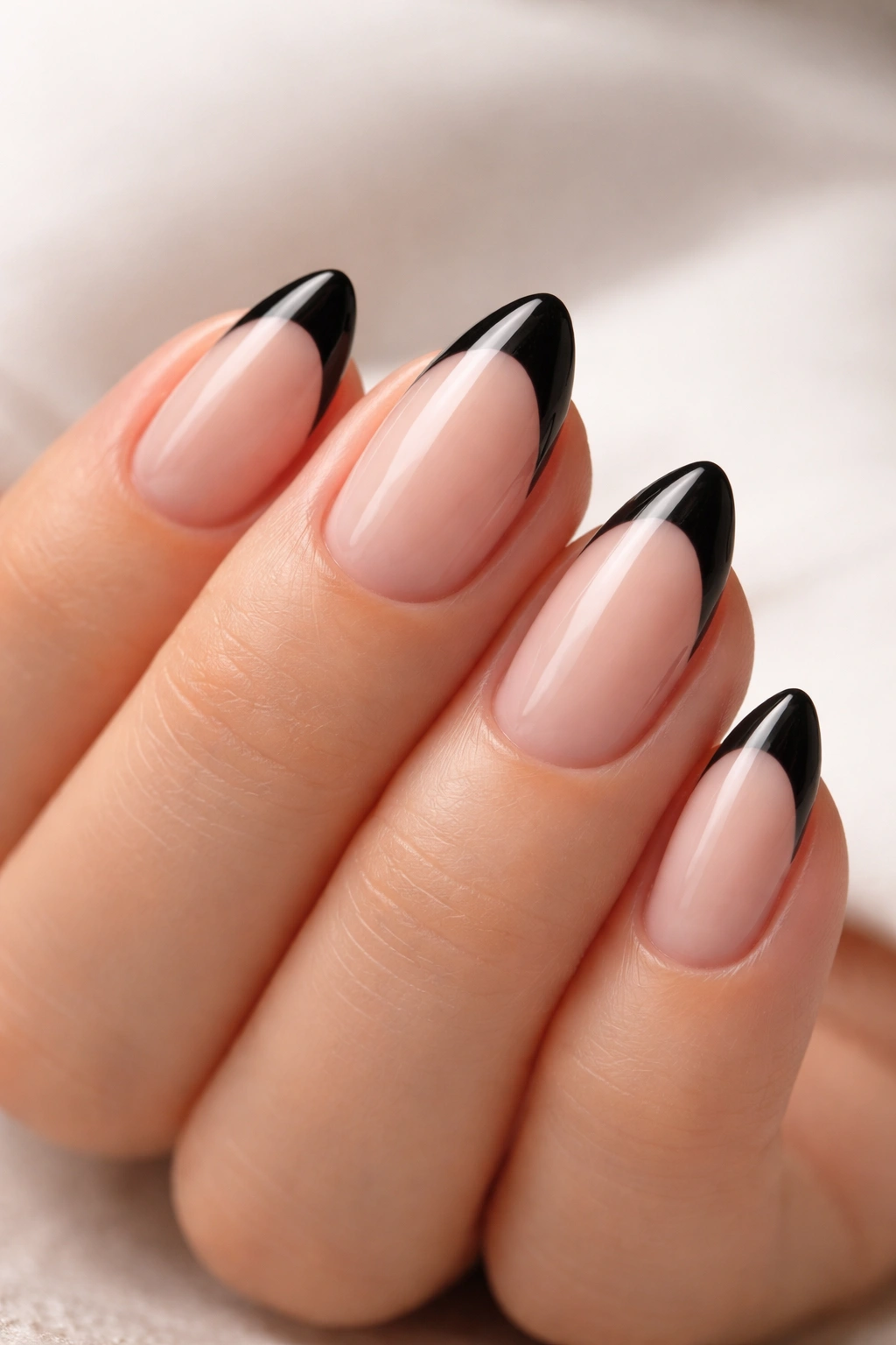 Close-up of short oval nails with pointed black tips on a neutral background