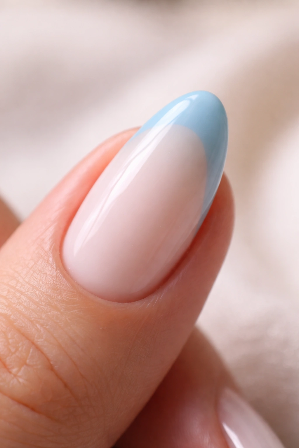 Close-up of almond nail with milky white base and powder blue tip.