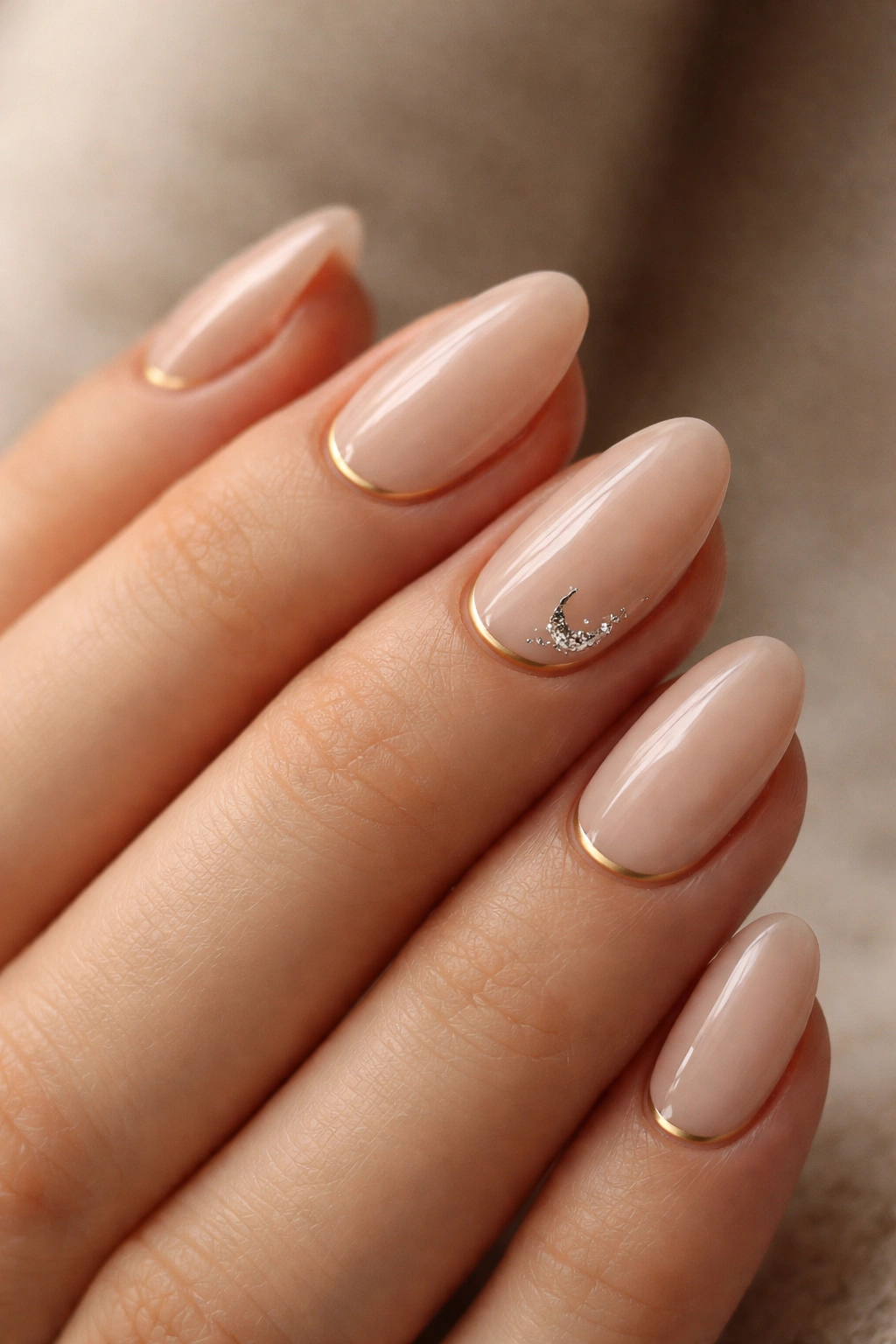 Close-up of short almond nails with delicate gold line and silver crescent