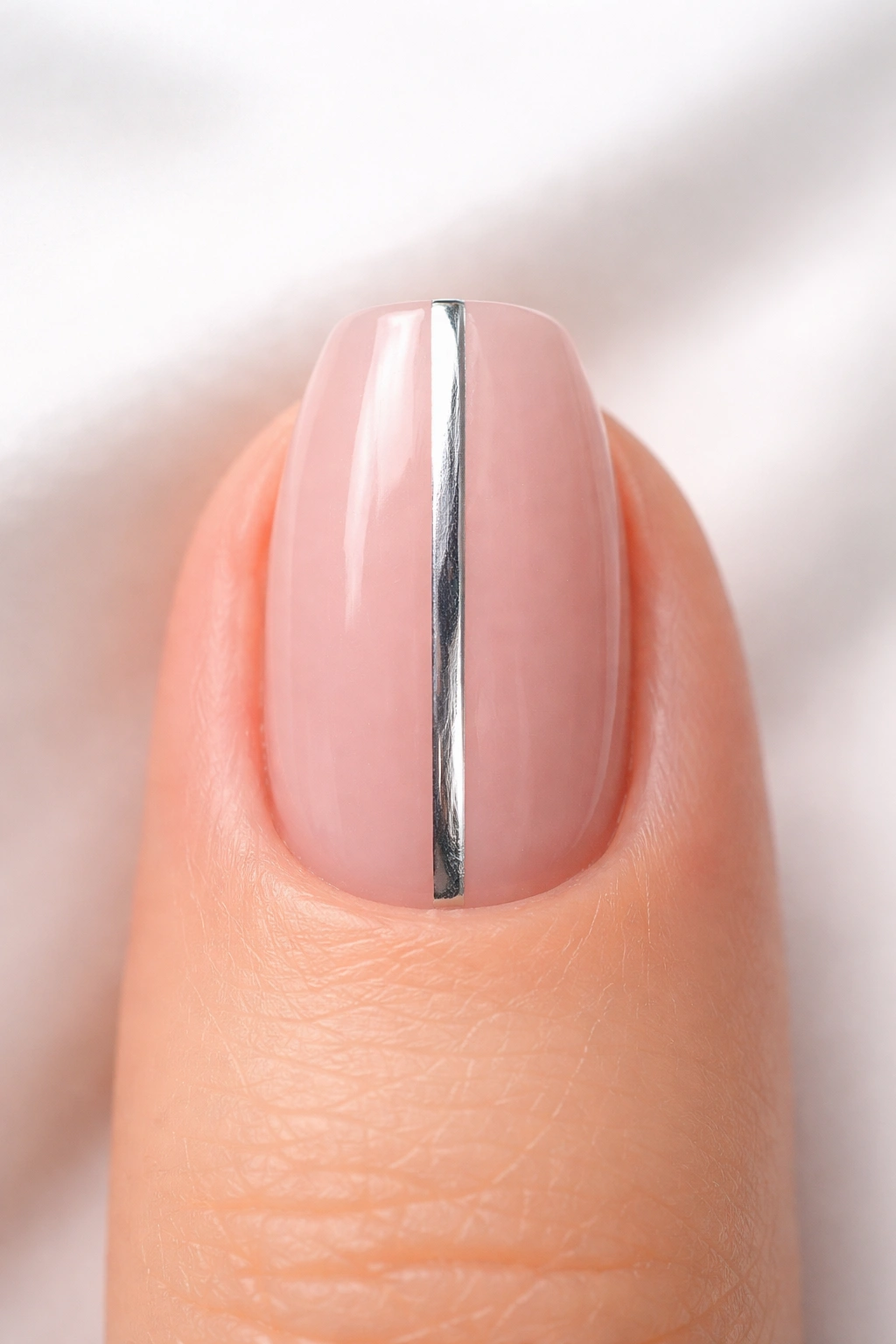 Close-up of a short ballerina nail with a centered chrome stripe on a nude base
