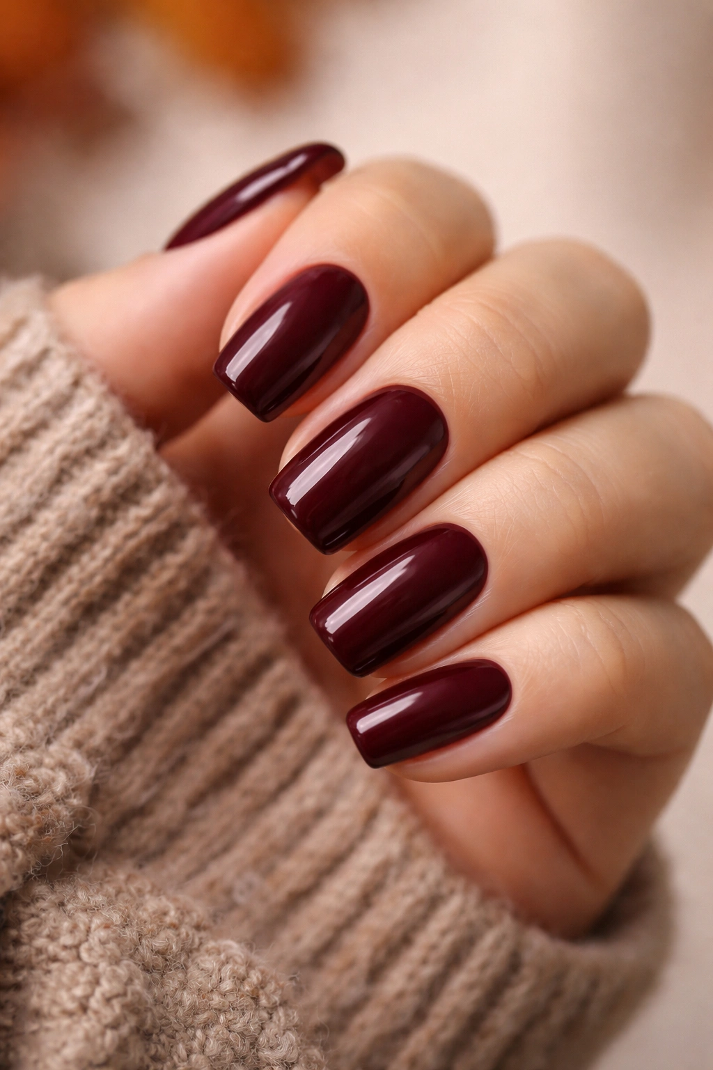 Close-up of nails painted in a rich fall burgundy color with glossy finish