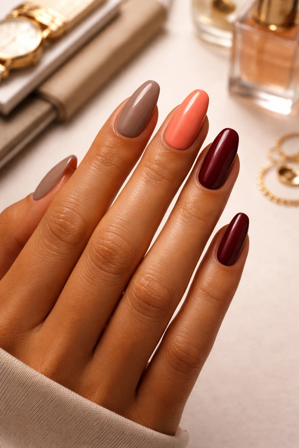 Hand showcasing taupe, coral, and burgundy nails for different occasions