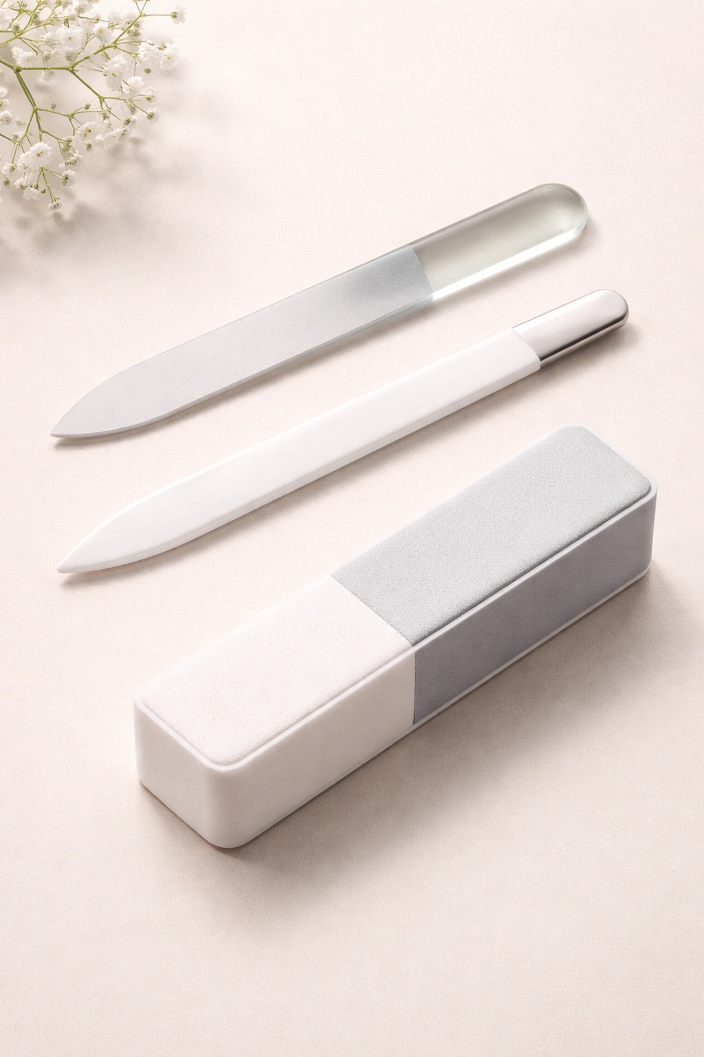 Flat lay of a glass nail file, ceramic nail file, and a nail buffer on a clean surface
