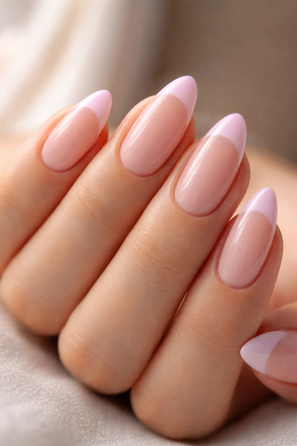 Close-up of almond nails at medium length with pink French tips.
